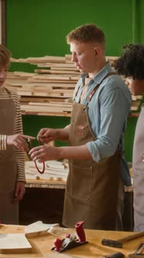 Vertical of Multiethnic Teenagers Checking Sharpness of Coping Saw