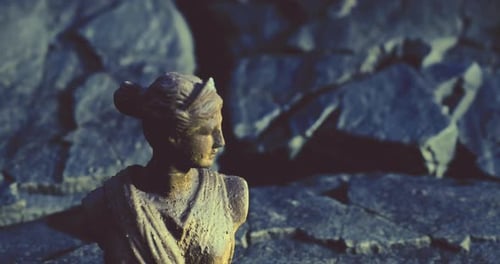 Skulptur einer historischen Figur, die in der Dämmerung auf felsigem Gelände positioniert ist