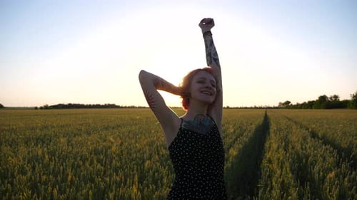 Young Female Hipster in Dress Posing on Camera on Green Barley Field at Sunset Carefree Punk Girl
