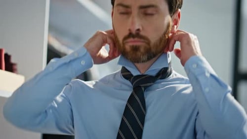 Handsome Man Adjusting Striped Tie in Bright Room