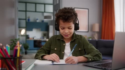 Child Studies at Desk with Headphones and Laptop