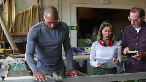 Carpenters Measuring Wood with Saw in Workshop