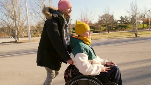 Man Pushing Friend in Wheelchair in Park