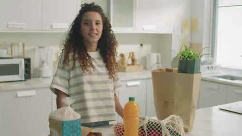 Portrait of Happy Girl by Kitchen Table with Groceries
