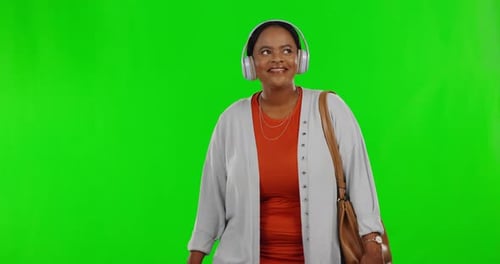 Happy, green screen and black woman with headphones, walking and travelling on a studio background