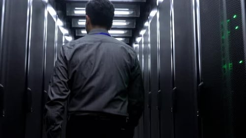 Rechenzentrumstechniker: Ein einsamer Techniker geht einen langen Korridor hell erleuchteter Serverracks entlang