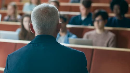 Clase frente a la cámara: un profesor universitario da una conferencia en un aula llena de estudiantes multiétnicos
