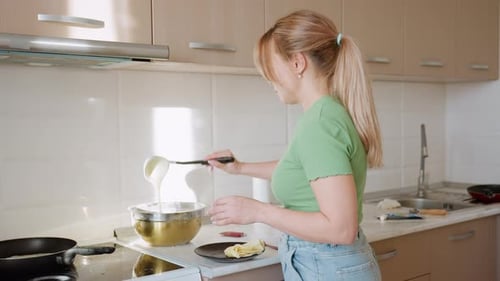 Woman preparing batter in a sunlit kitchen