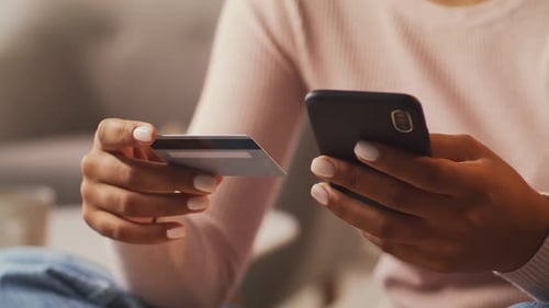 Woman Holds Credit Card while Using Smartphone