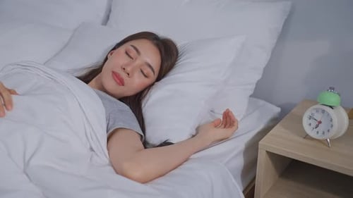 Asian beautiful tired young woman turn off an alarm clock in morning.