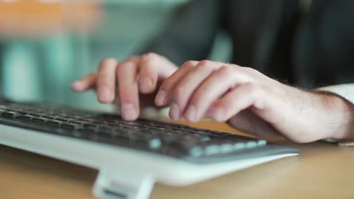 hands close up of business man in office typing on keyboard. male, employee, entrepreneur in a suit