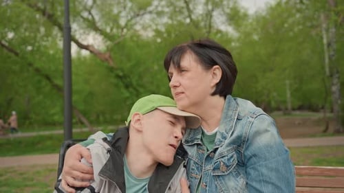 Caring Woman Comforting Teenager in Park on Bench