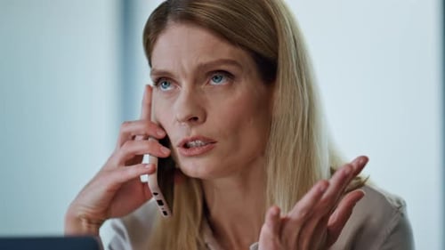 Woman Anxiously Talking on Cell Phone in Office