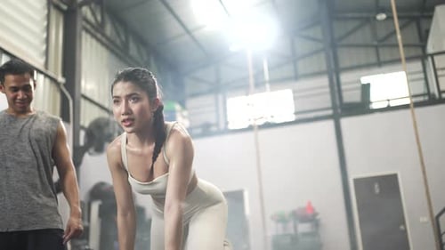 Pretty woman and instructor are exercising at a fitness center.