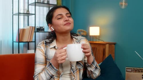 Relaxed woman sips tea and enjoys music