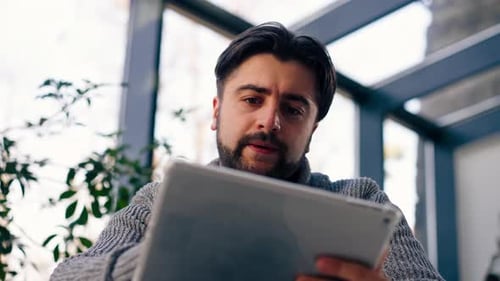 Low Shot Closeup of Young Guy Office Worker Against the Background of a Window Sitting on a Chair