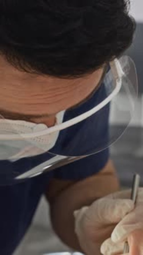 Vertical of Dentist Examining Patient Teeth with Dental Tools on Treatment Chair
