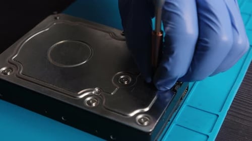 Serviceman Disassembling Hard Data Disk Drive to Repair
