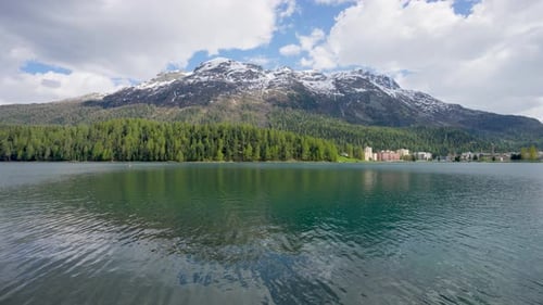 Snow-covered mountains, clear lakes, lakeside houses and coniferous forests.