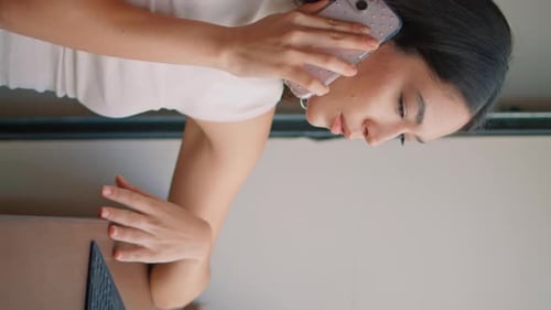 Asian Business Lady Calling Cellphone at Workplace in Cafeteria Closeup Vertical