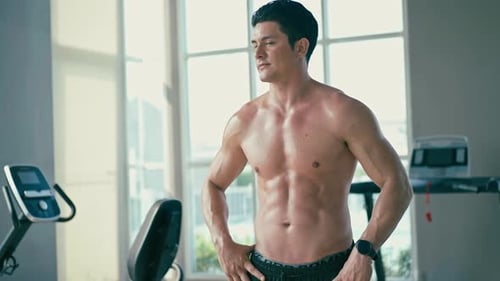 Shirtless Man Stands Sweaty in Gym