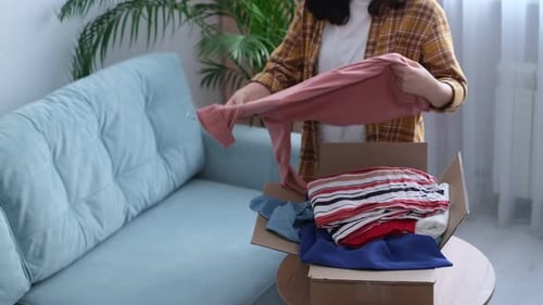 Woman Sorting Clothing for Donation Indoors