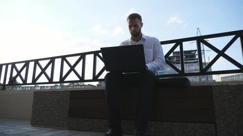 Successful Entrepreneur Works on Notebook Sitting on Bench at Town
