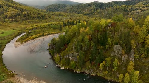Aerial view of a winding river in an autumn forest landscape