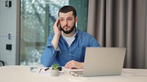 Man with Headache Sits at Desk in Office