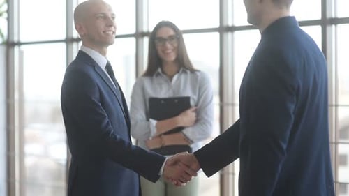 Businessmen Shake Hands in Bright Modern Office