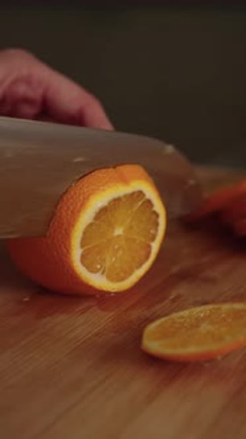 Vertical Cropped Shot of Female Chef Cutting Fresh Juicy Orange Into Slices on Wooden Cutting Board