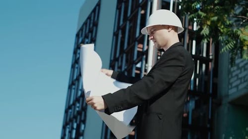 portrait of a successful handsome engineer, architect, builder, businessman in a white helmet, in a