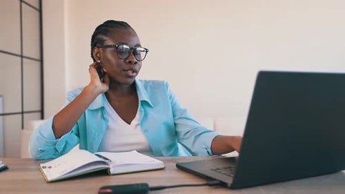 Woman with Glasses Working on Laptop at Desk