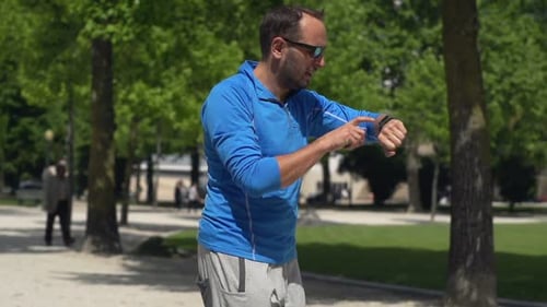 Man Jogging and Checking Pulse on Smartwatch in City Park, Super Slow