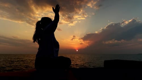 Femme pratiquant le yoga avec silhouette de mains de prière au coucher du soleil