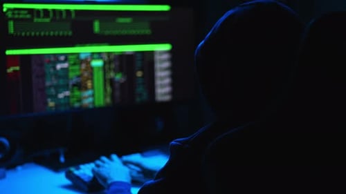 Tracking-Aufnahme eines heimlichen Hackers, der ein Sweatshirt mit Kapuze trägt und auf der Tastatur zu Bruch geht