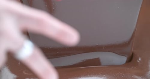 Chocolate sauce pouring over shiny surface dessert preparation