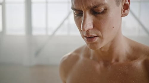 Porträt eines erschöpften jungen athletischen Mannes, der sich nach einem intensiven Indoor-Training entspannt und stark einatmet