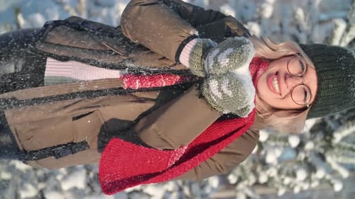 VERTICAL VIDEO POV Smiling Woman Blowing Snow at Sunny Winter Forest Closeup Slow Motion
