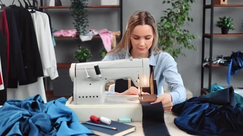 Focused Woman Seamstress Sews Clothes Textile Details Electric Sewing Machine at Tailoring Atelier