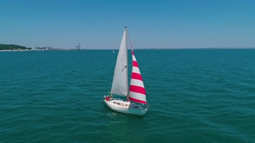 Beautiful boat with sails on water. Yacht sailing in sea on the coastline background.