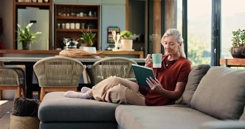 Senior Woman Relaxes on Couch with Tablet and Coffee