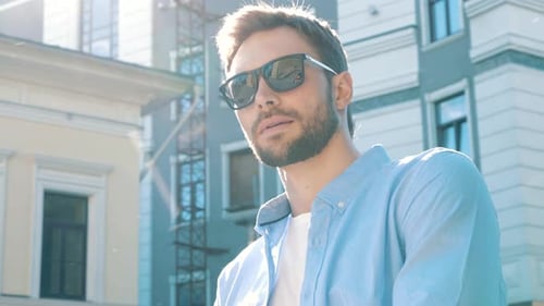 Smiling Man Takes off Sunglasses in Urban Setting
