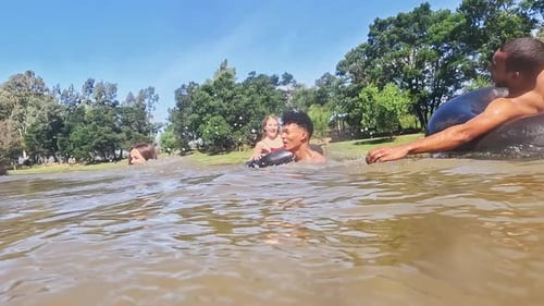 Camp, swimming and friends in lake in nature on holiday, summer vacation and weekend