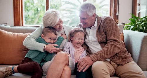 Grandparents Embracing Grandchildren on Couch Together