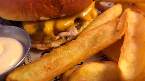 Köstlicher doppelter Cheeseburger mit Pommes und Sauce, Fastfood-Restaurant, ungesundes Essen, 4K-Aufnahme
