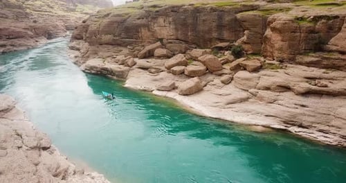 boat riding on a green emerald color river water in a clay rock cliff valley in nature cloudy weathe