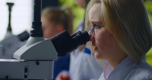 Schulmädchen schaut im Bildungslabor durchs Mikroskop Kluges Teenager-Mädchen, das Biologie studiert