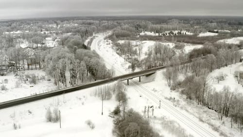 Vol hivernal. Le train approche du pont. Exagère les jours. Couleur neutre. Des arbres gelés.