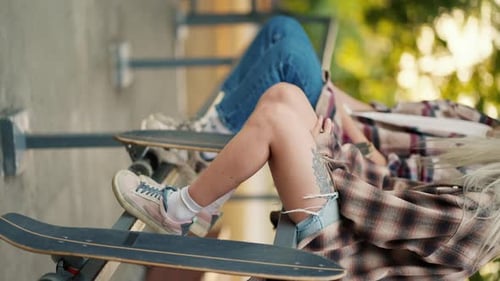 Vertical Video Shooting Close Up of Girls in Plaid Shirts Sitting on the Fence in a Skate Park Near